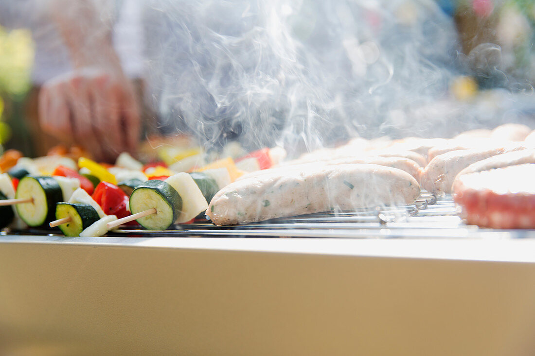 Sausages and vegetable steaming on barbecue grill