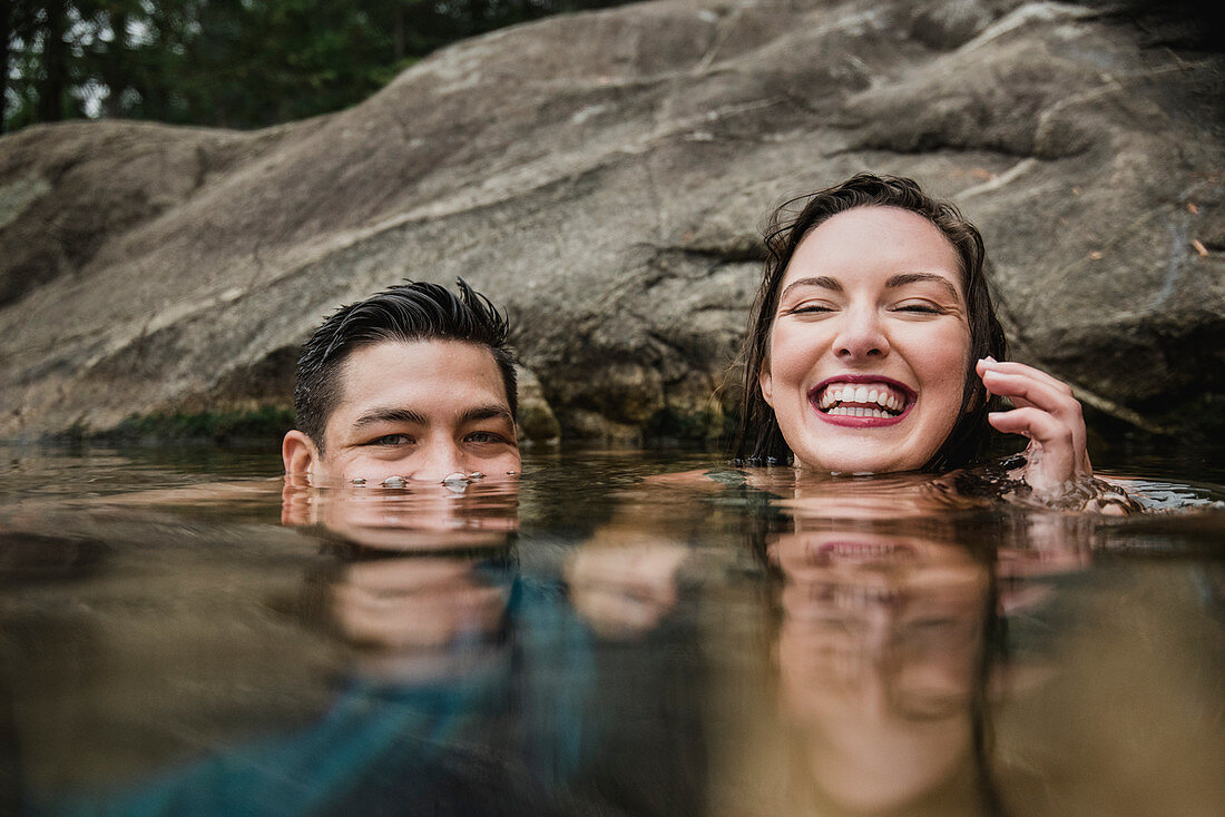 Portrait playful couple swimming in lake