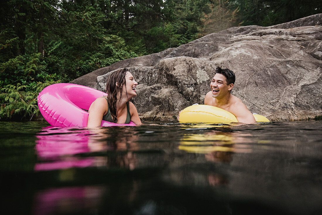 Young couple floating in inflatable rings on lake
