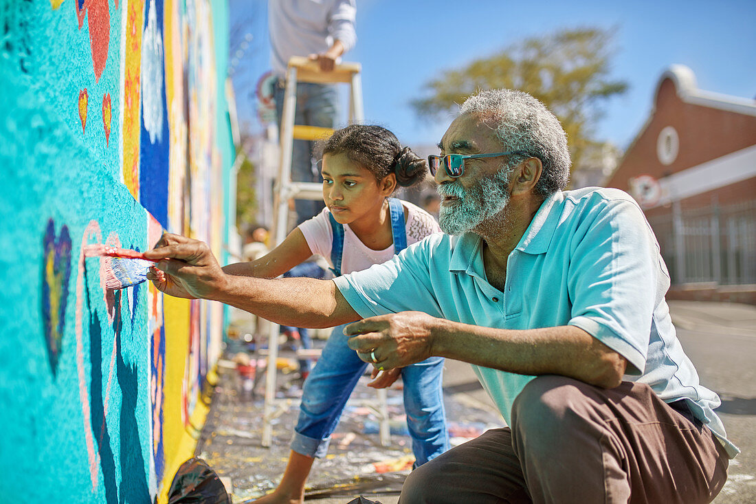 Grandfather and granddaughter volunteers painting mural