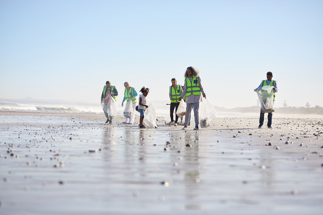 Volunteers cleaning up litter on wet sand beach