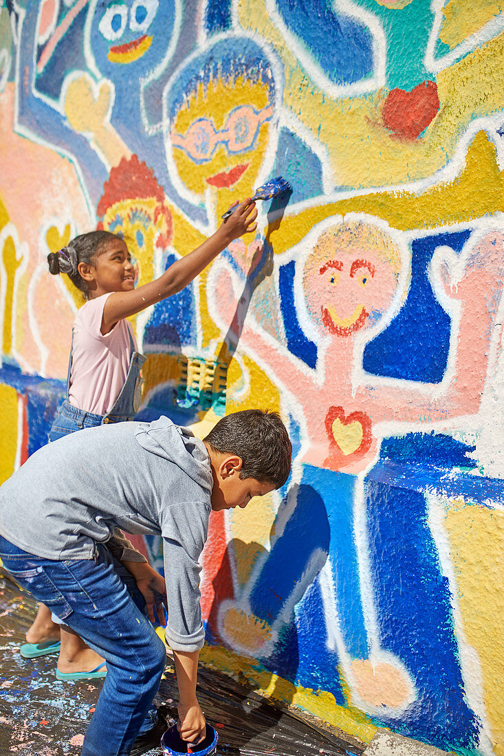 Children painting vibrant mural on wall