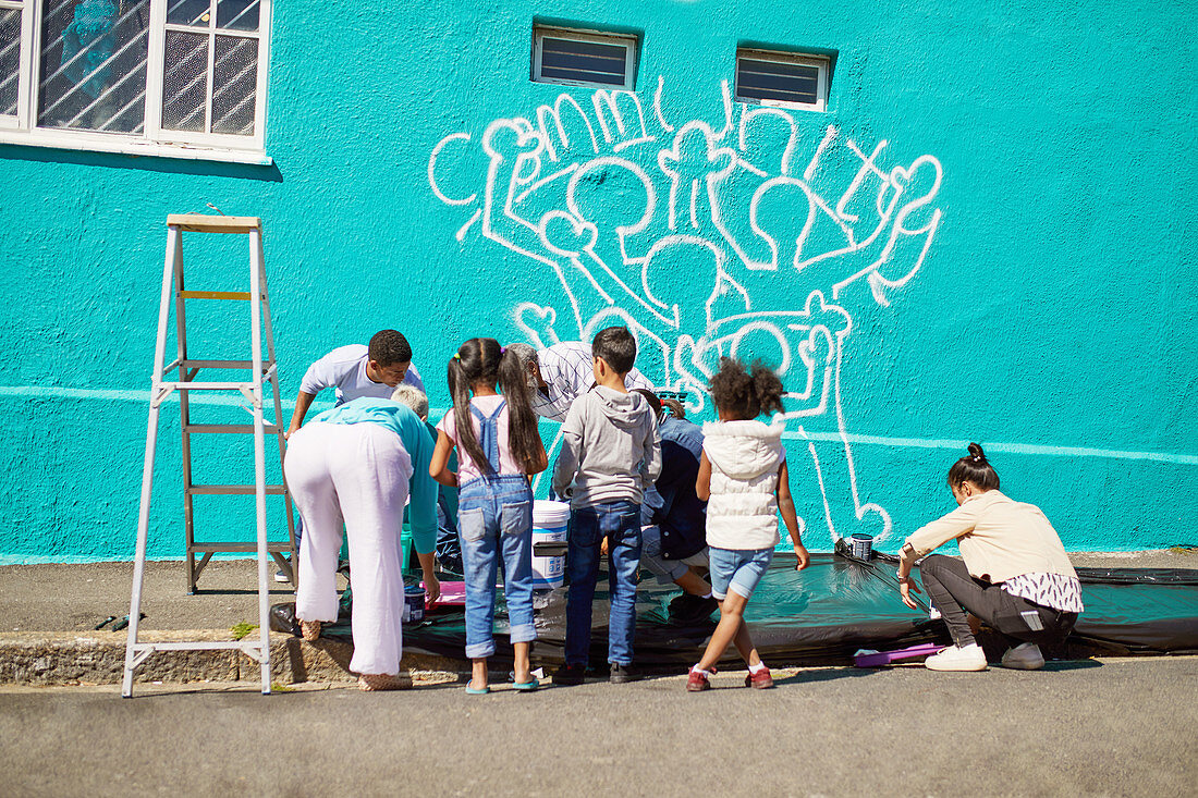 Kid volunteers painting community mural on wall