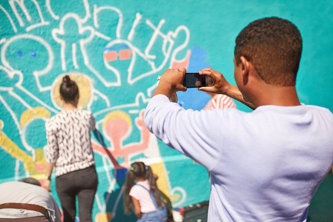 Man photographing community mural on wall