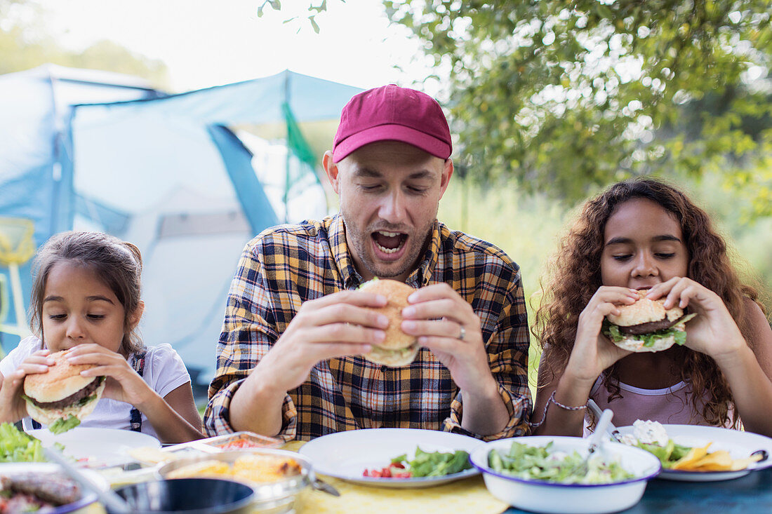 Father and daughters eating barbecue hamburgers