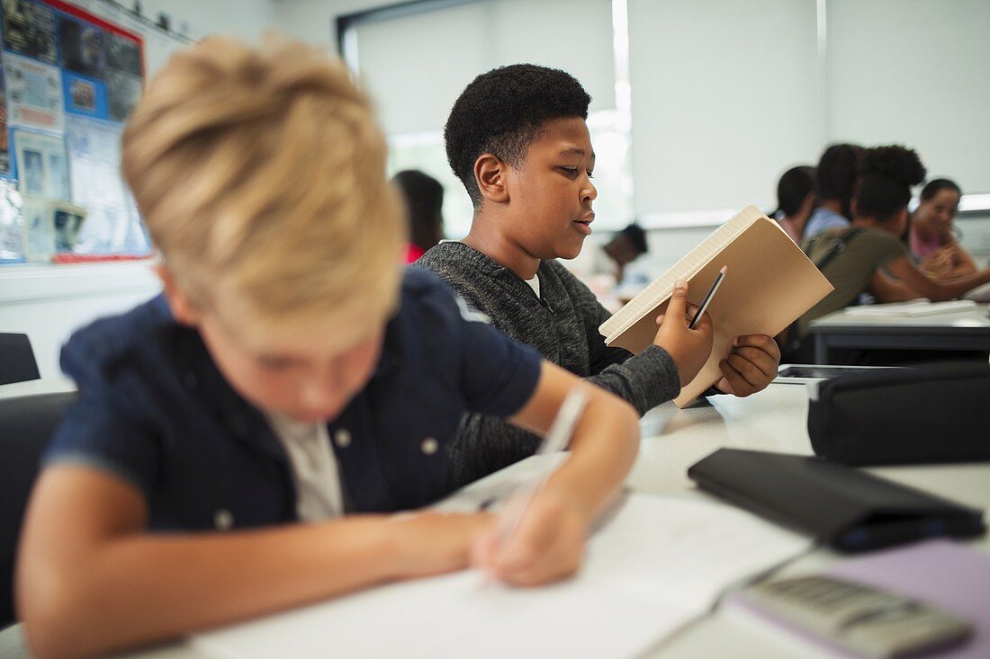 school boy opening notebook at desk