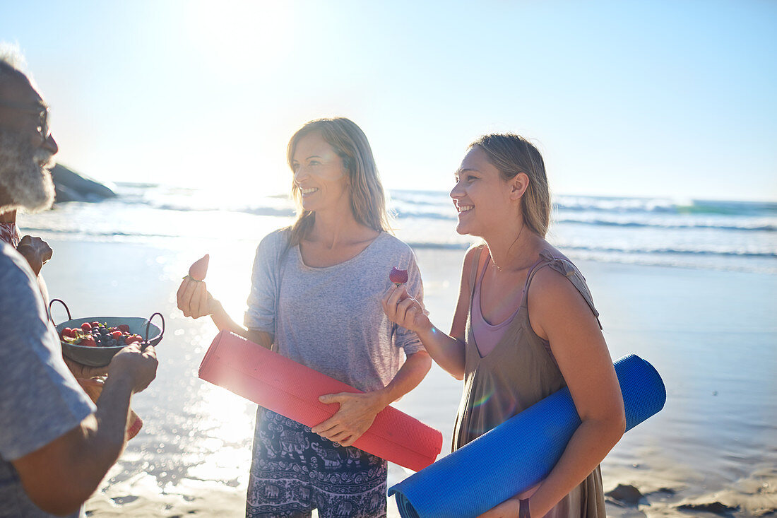 Mother and daughter with yoga mats eating fresh berries