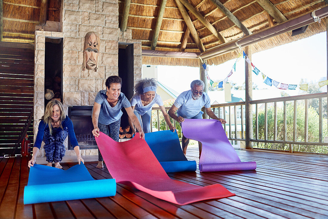 People unrolling yoga mats in hut
