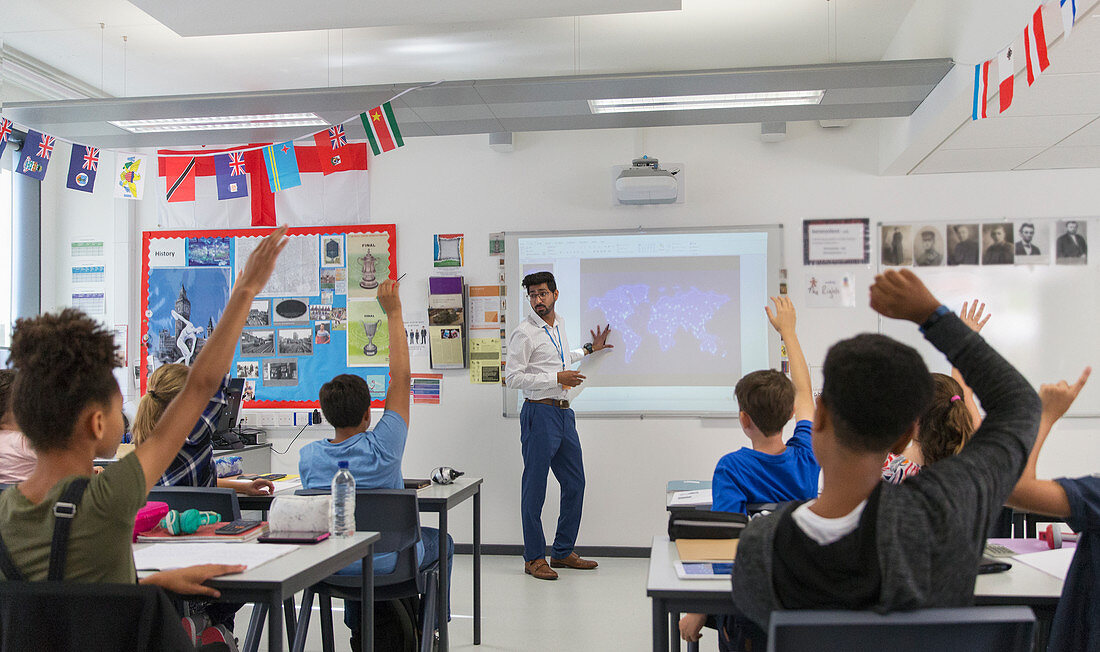 school students raising hands for teacher leading lesson