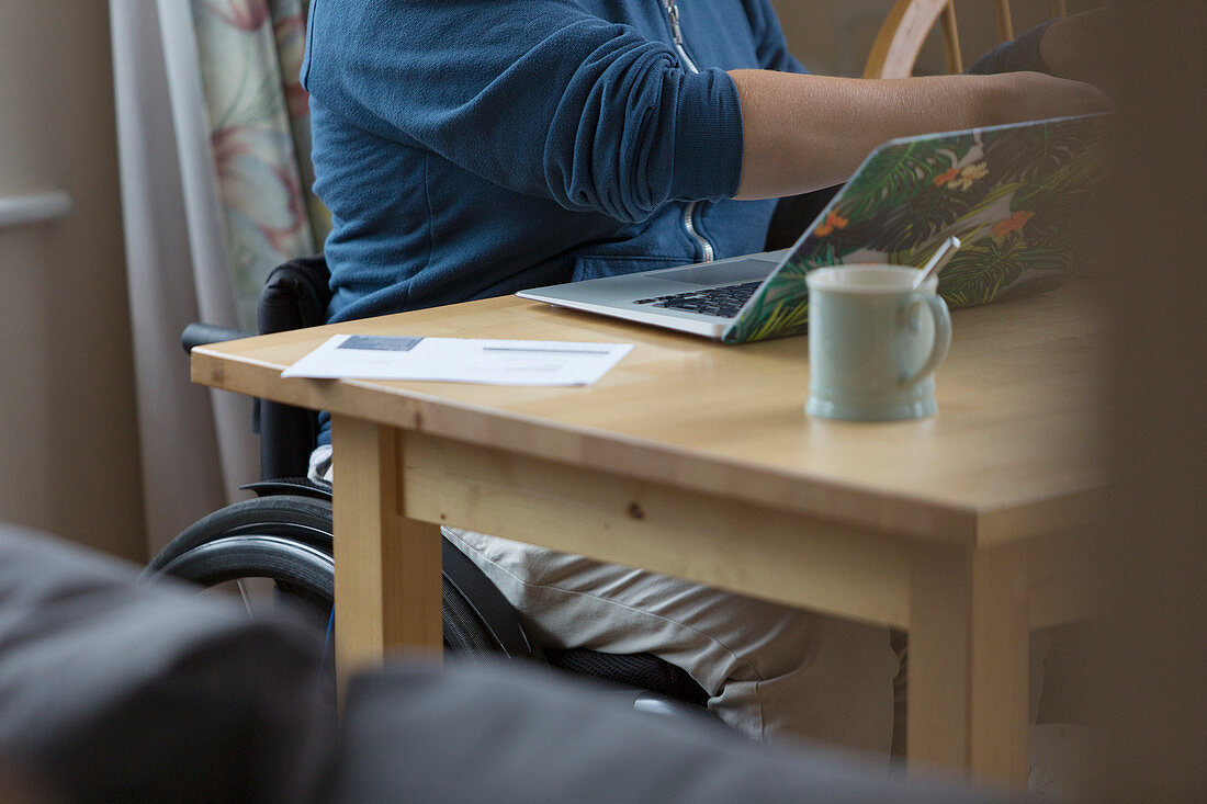 Young woman in wheelchair using laptop