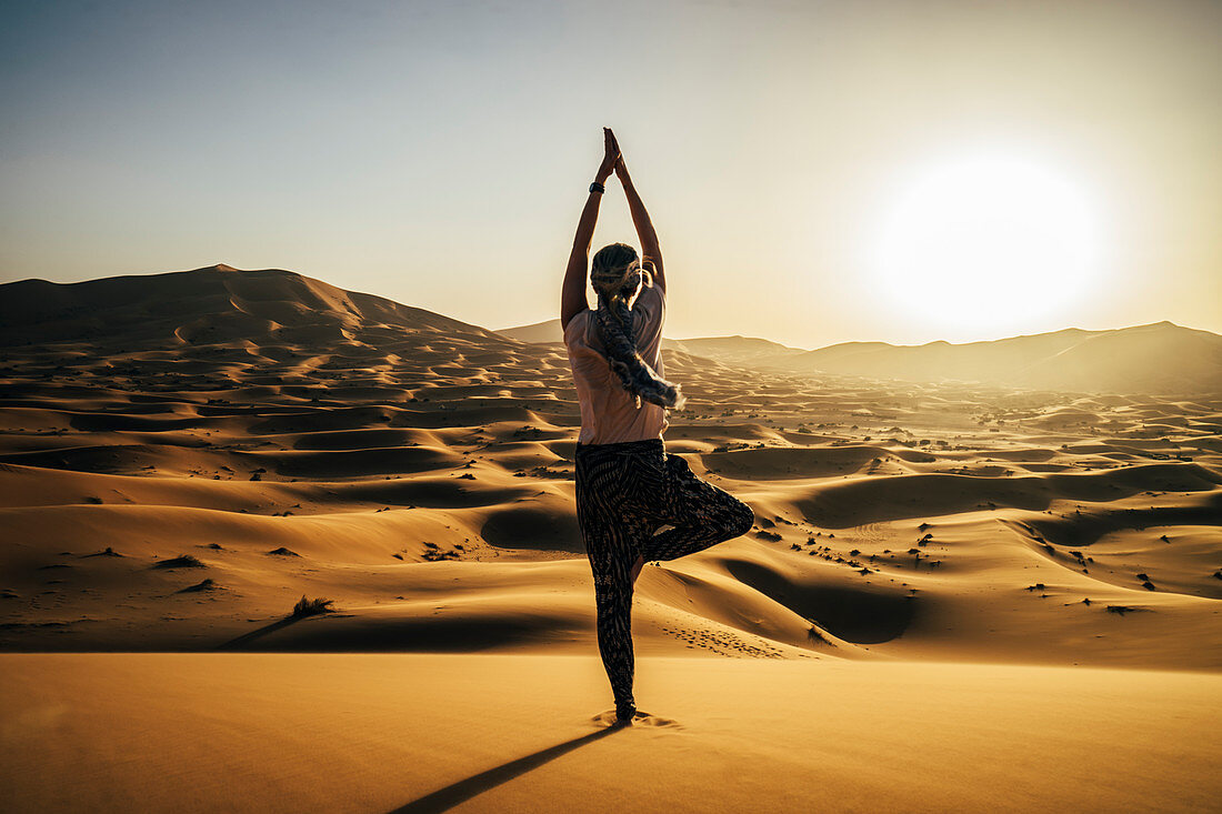 Serene woman standing in yoga tree pose in desert