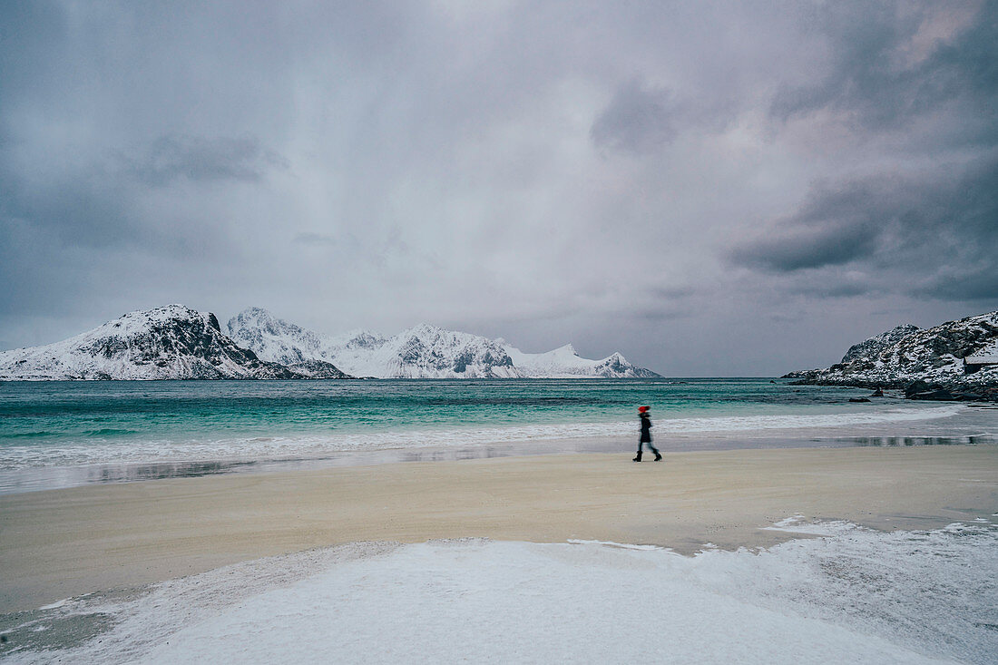Woman walking on cold, snowy beach, Lofoten Islands, Norway