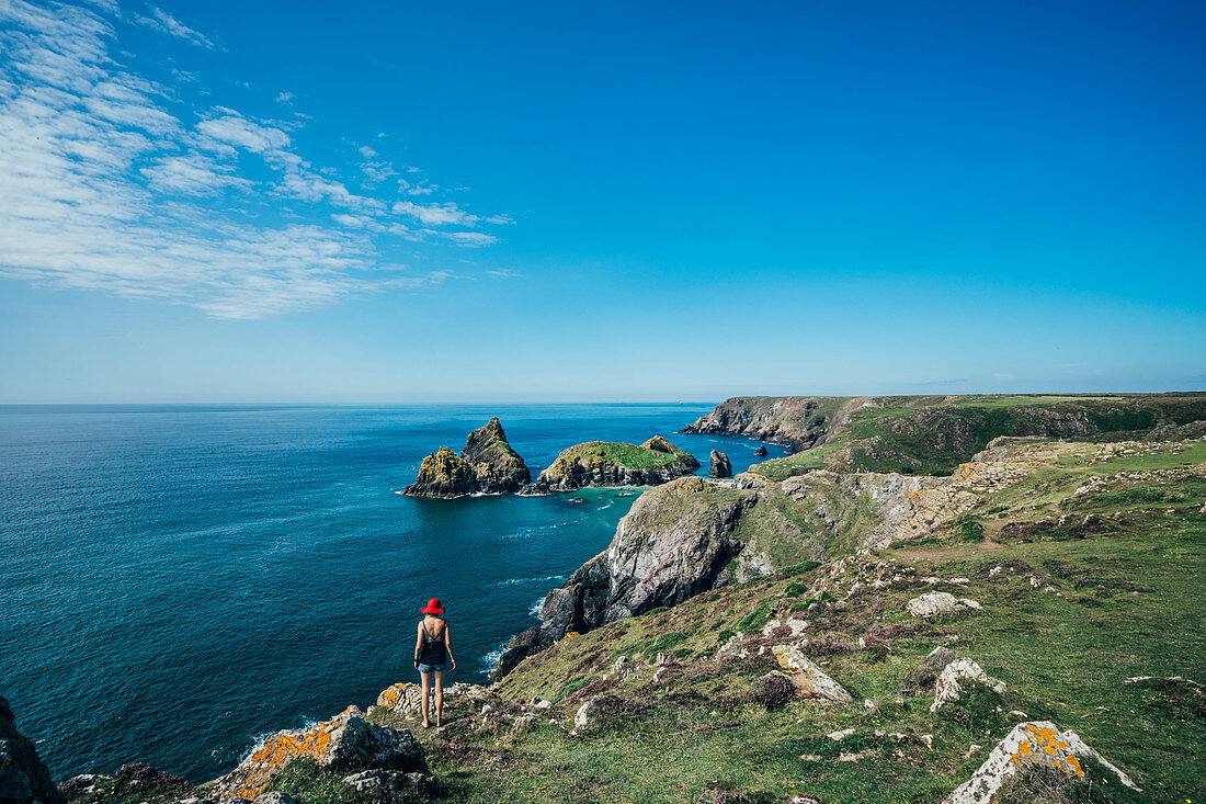 Woman standing on cliffs with ocean view, Cornwall, UK
