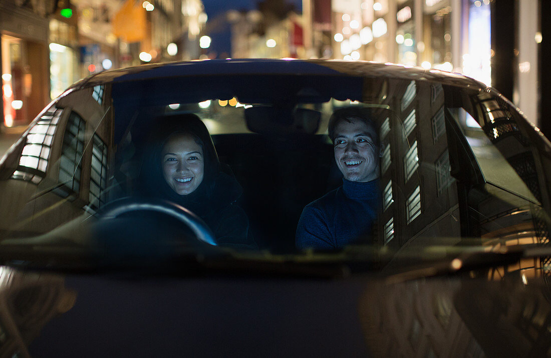 Smiling couple driving on city street
