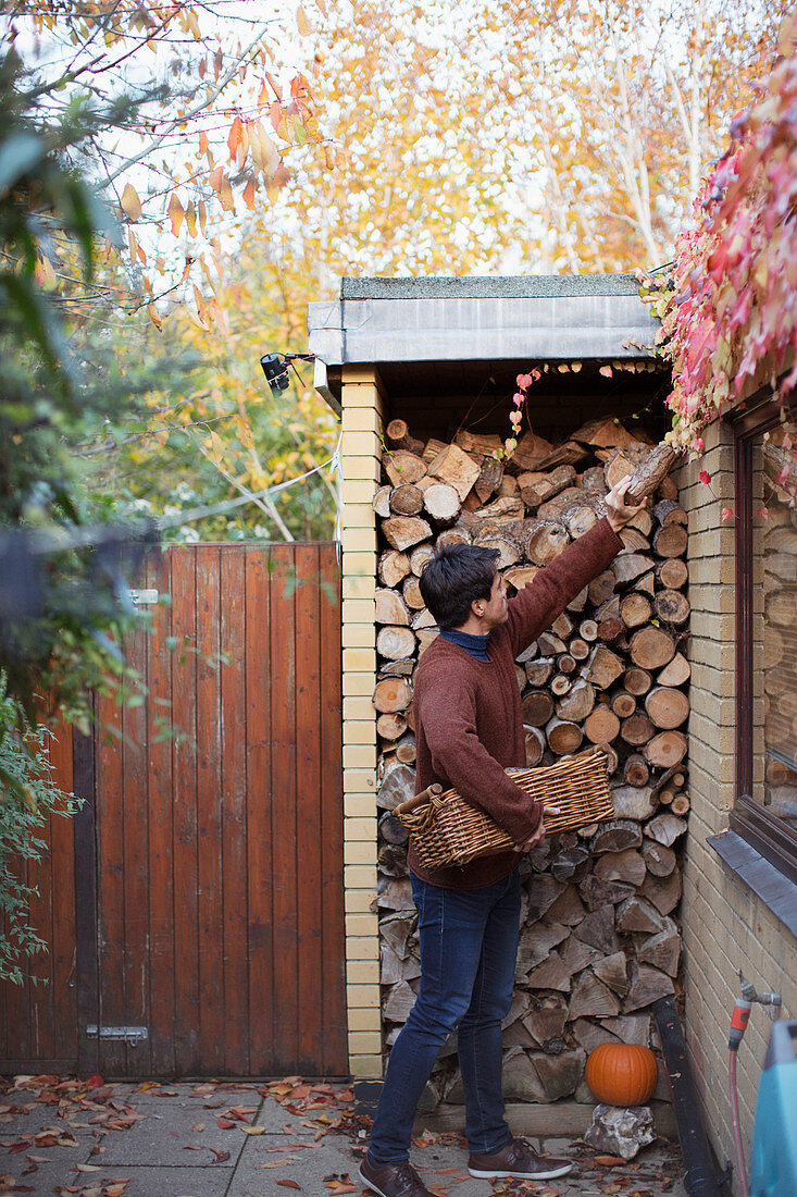 Man reaching for firewood on autumn patio