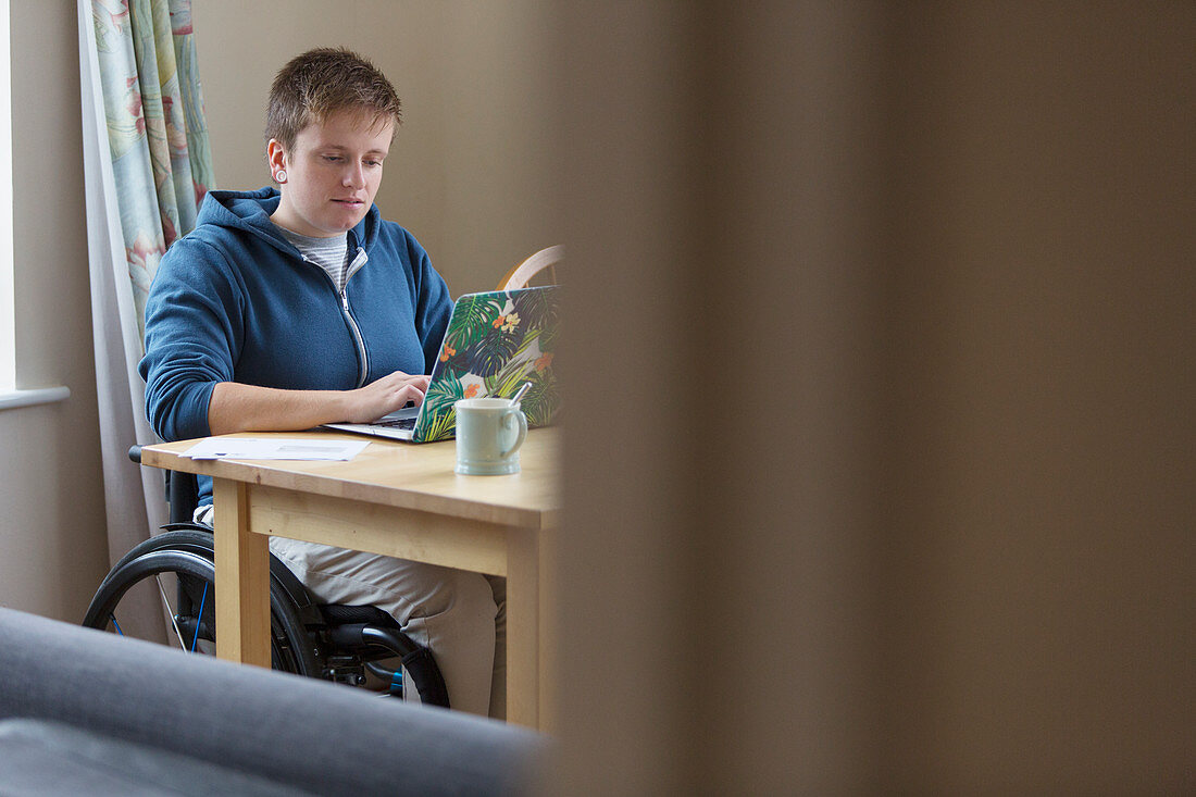 Young woman in wheelchair using laptop