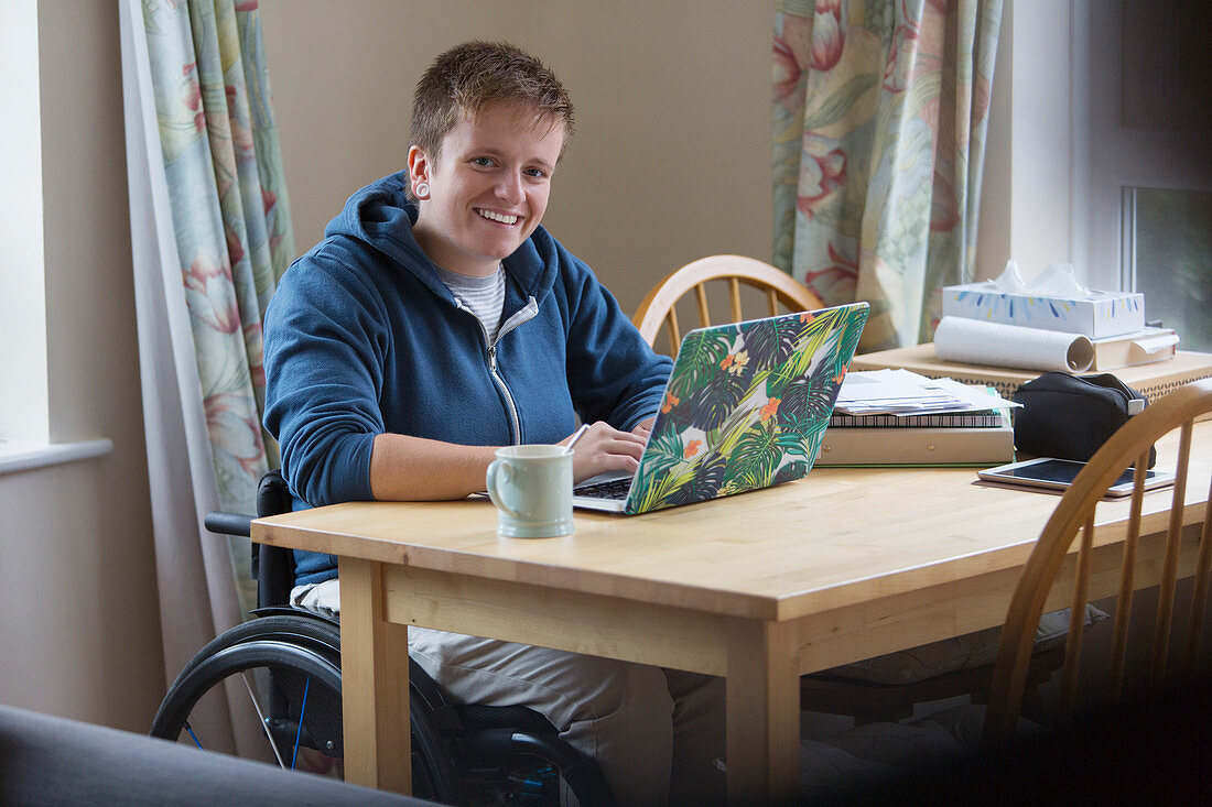 Portrait woman in wheelchair using laptop