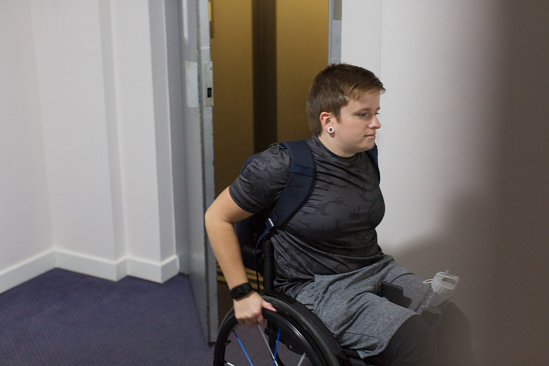 Young woman in wheelchair getting out of elevator