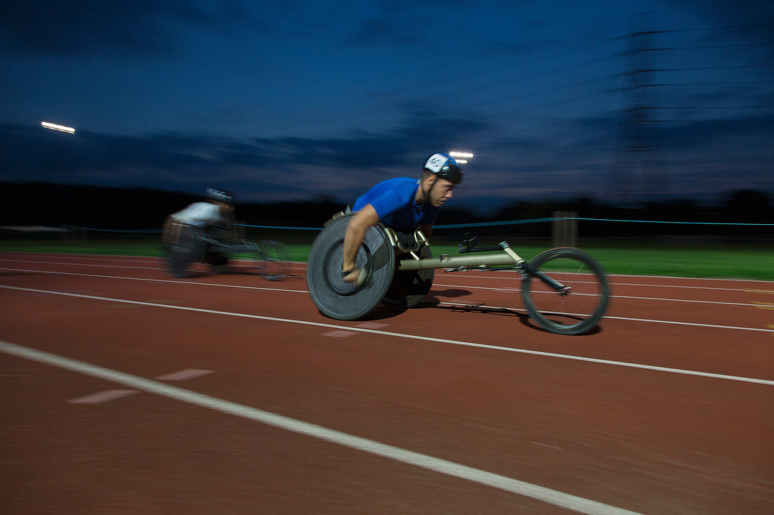 Determined paraplegic athlete in wheelchair race at night