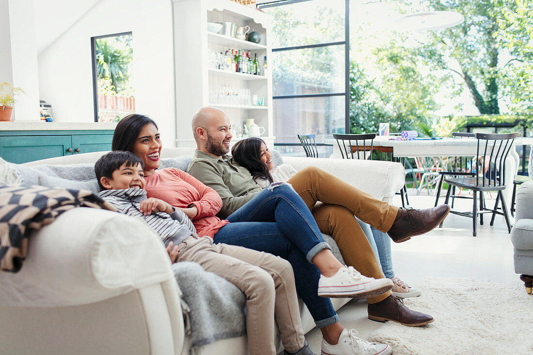 Family watching TV on living room sofa