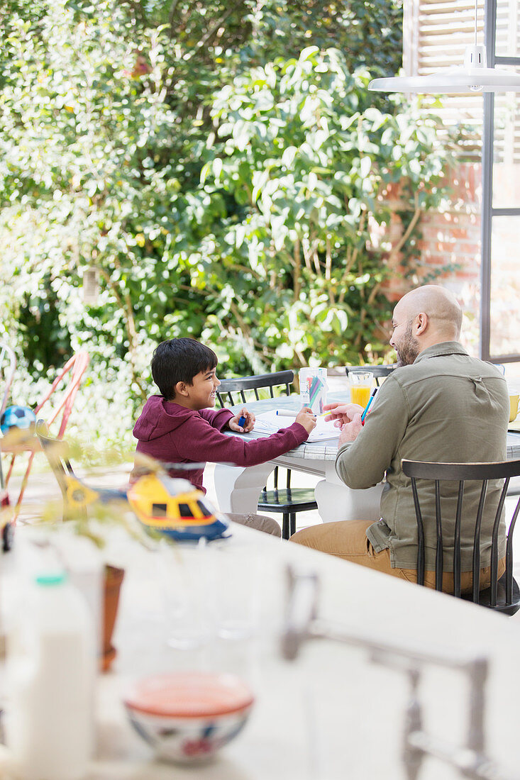 Father and son colouring at table