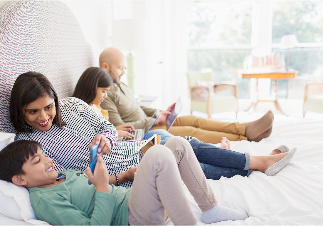 Family using technology on bed