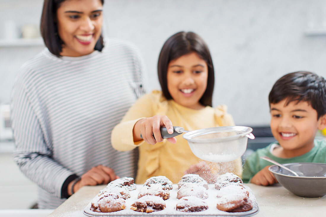 Mother and children baking muffins in kitchen