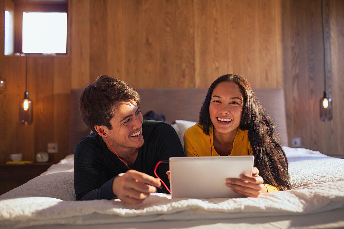 Portrait happy couple sharing laptop on bed
