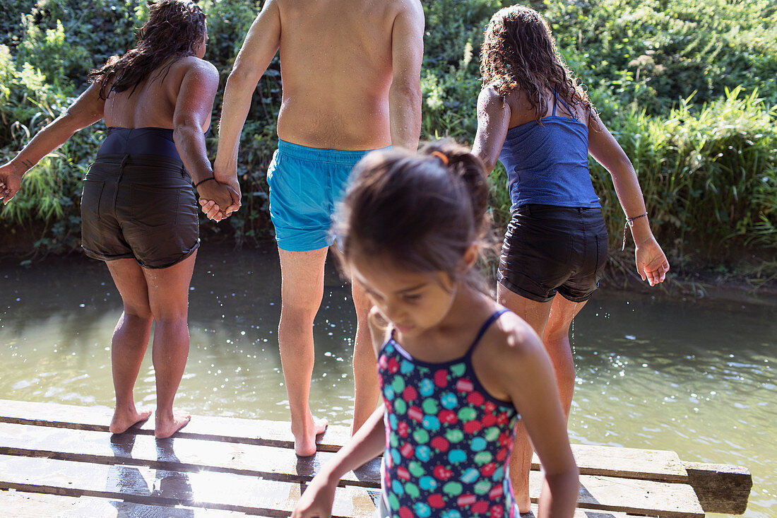 Family playing, jumping off dock into river
