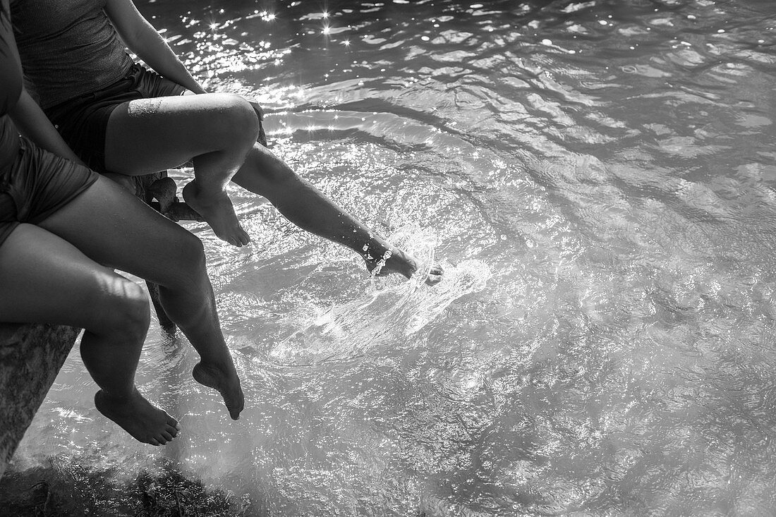 Mother and daughter splashing feet in river