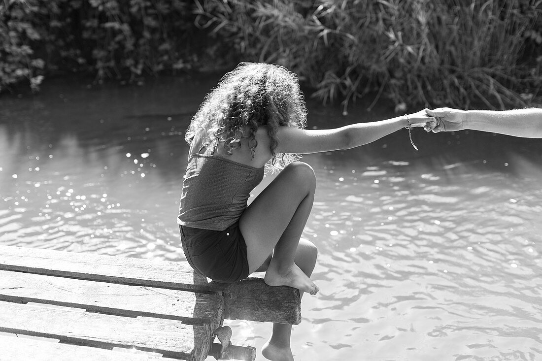 Girl sitting at the edge of riverside dock