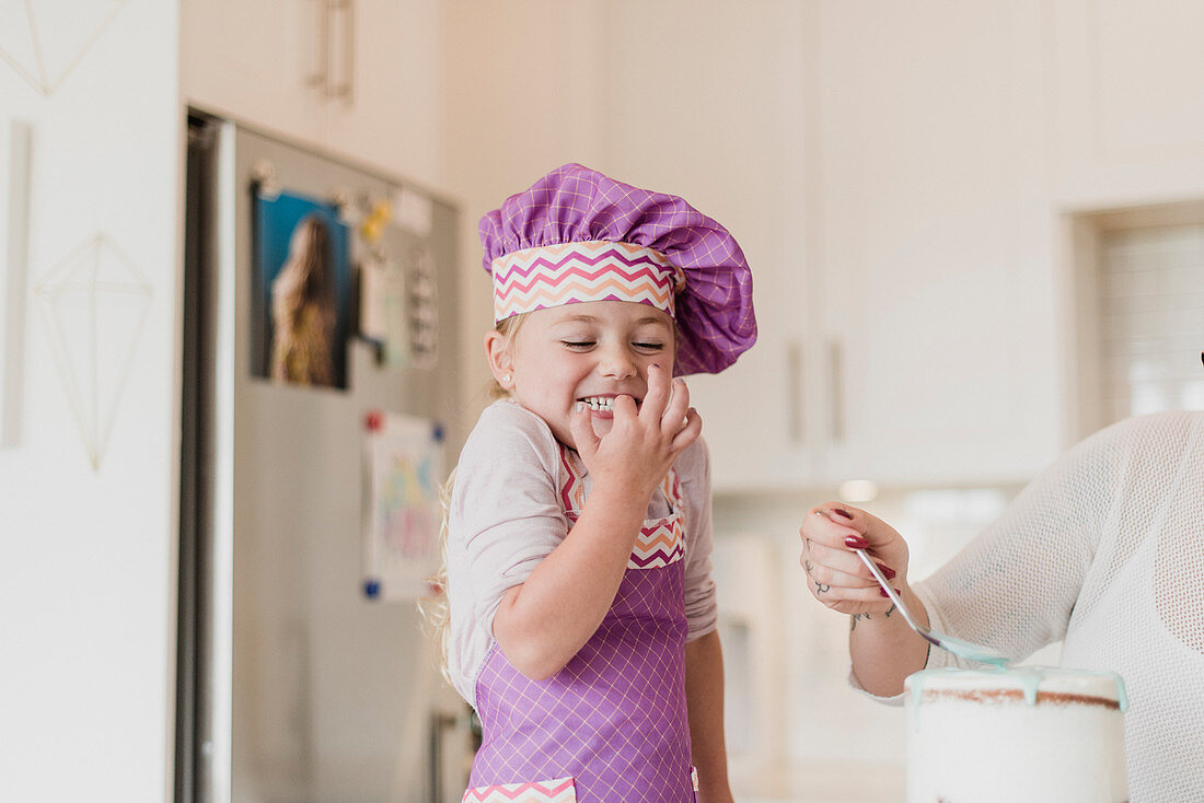 Happy, cute girl in chef's hat baking in kitchen