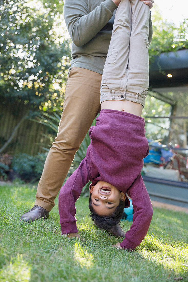 Playful boy hanging upside down in backyard