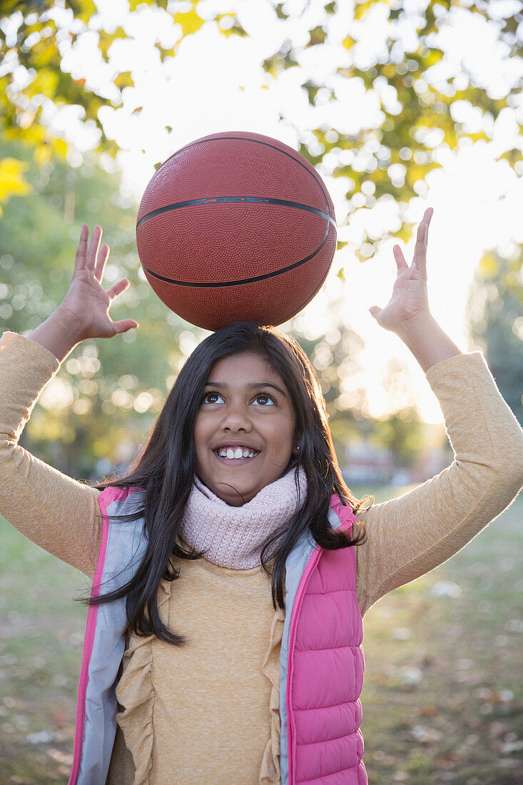 Portrait cute girl balancing basketball on head