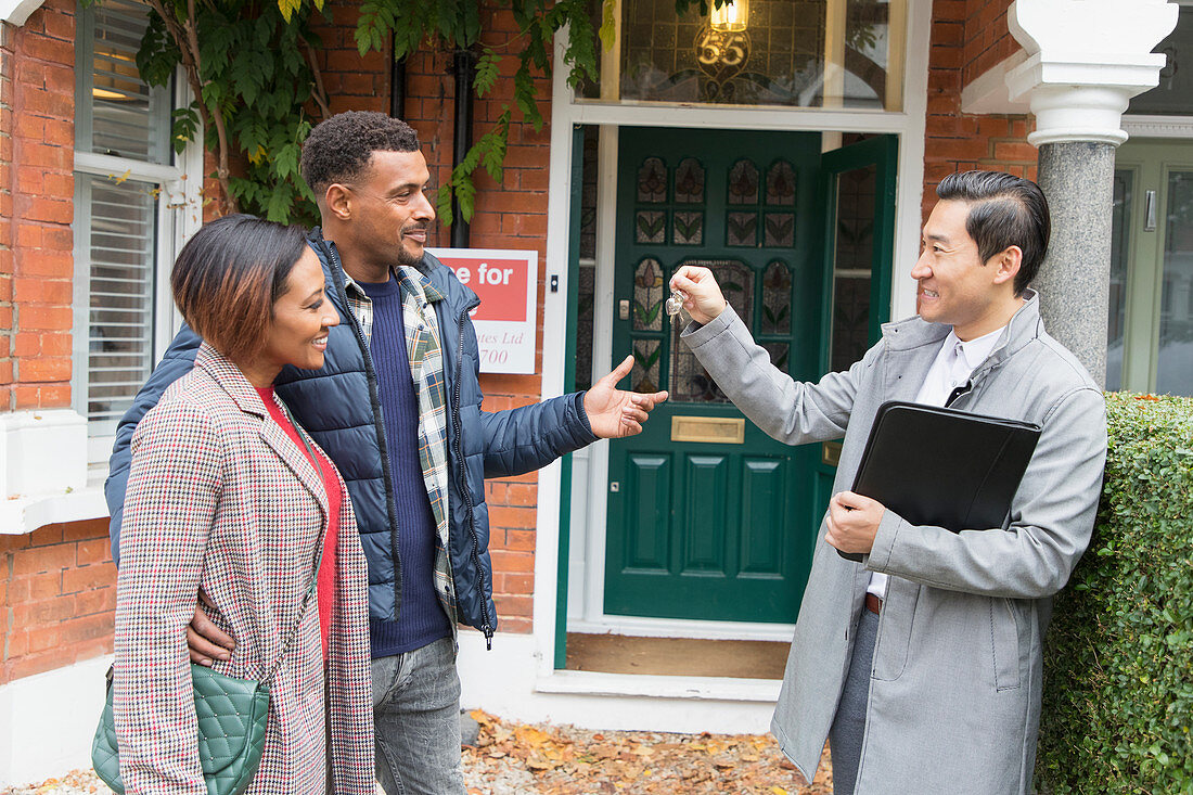 Real estate agent giving house keys to couple