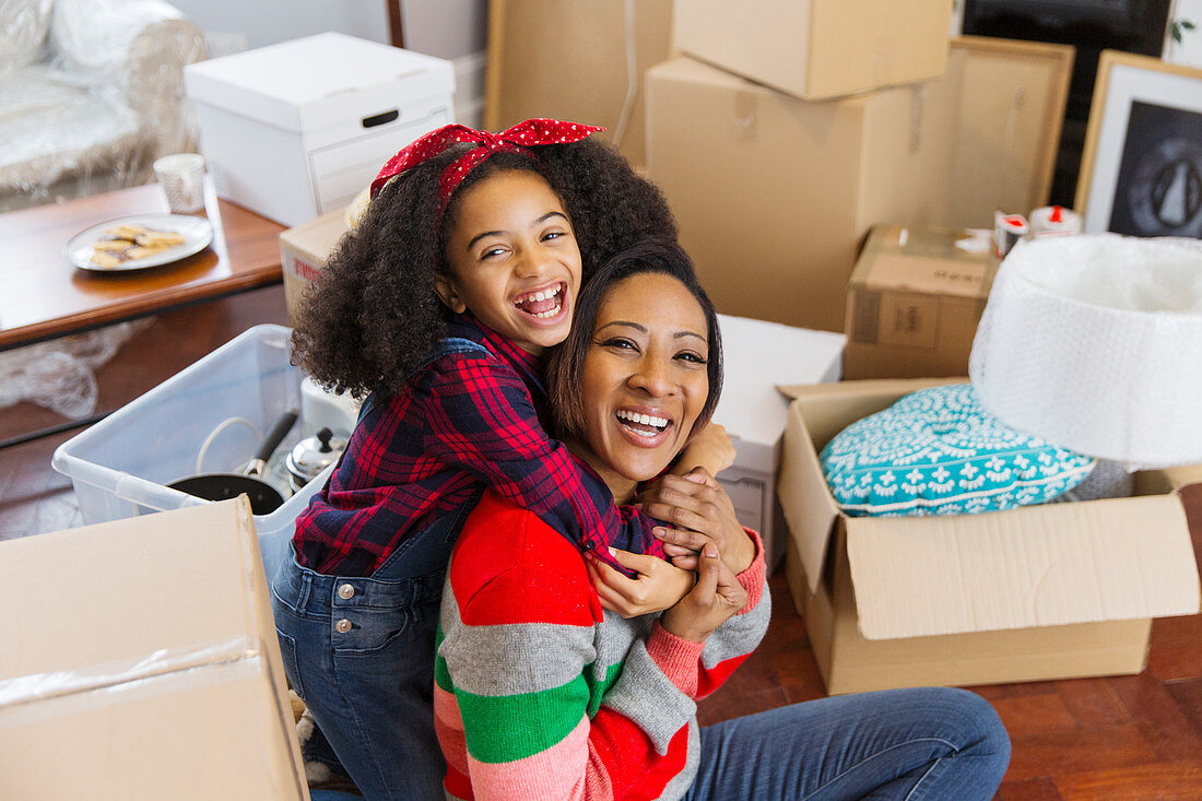 Mother and daughter hugging among boxes