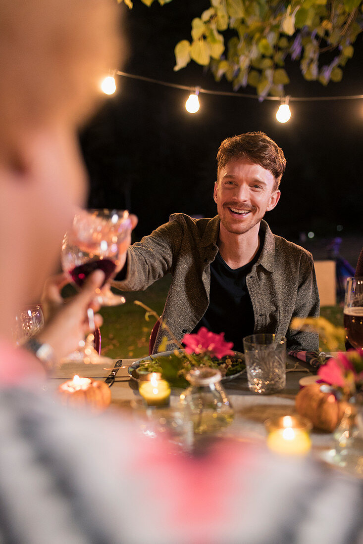 Happy man toasting wine glass at dinner garden party