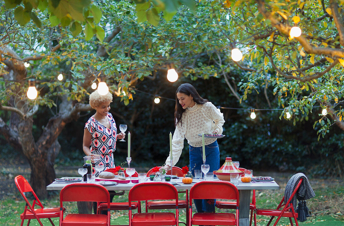 Women friends setting table for dinner garden party