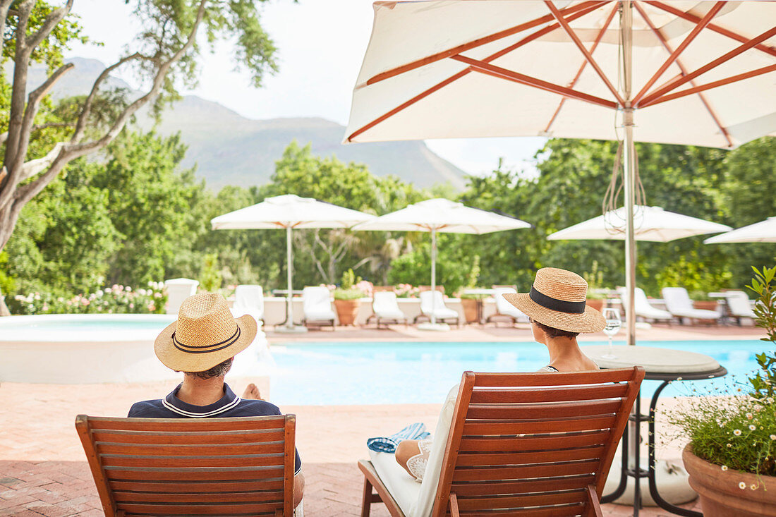 Couple relaxing on lounge chairs at resort poolside