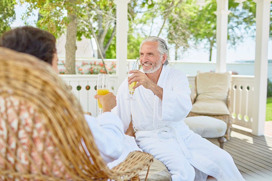 Mature couple in spa bathrobes drinking mimosas