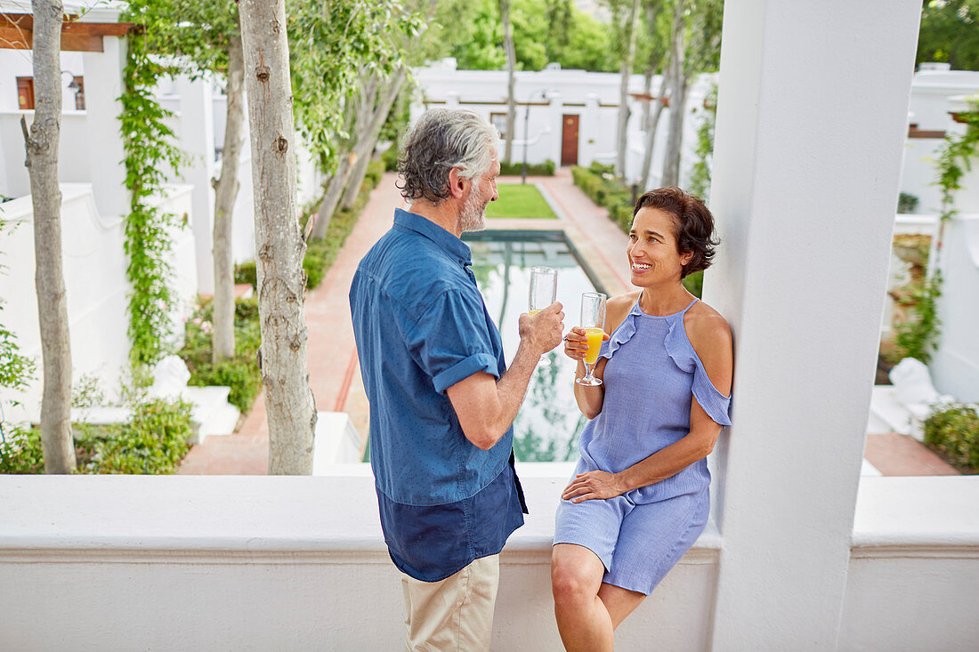 Mature couple drinking mimosas on hotel balcony