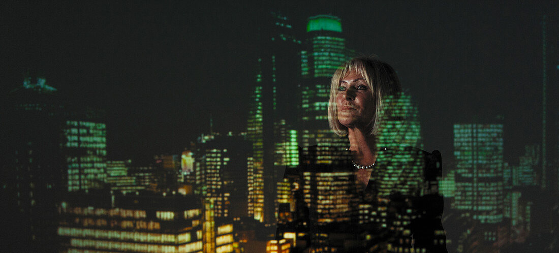 Businesswoman against highrise lights at night