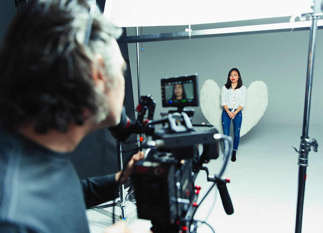 Photographer and young woman wearing angel wings