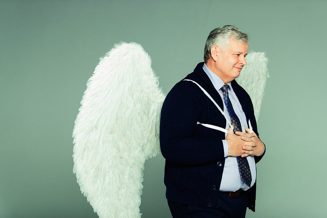 Smiling businessman wearing angel wings