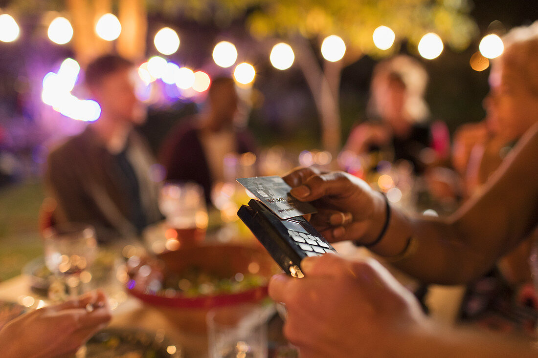 Woman paying for dinner with smart card on patio