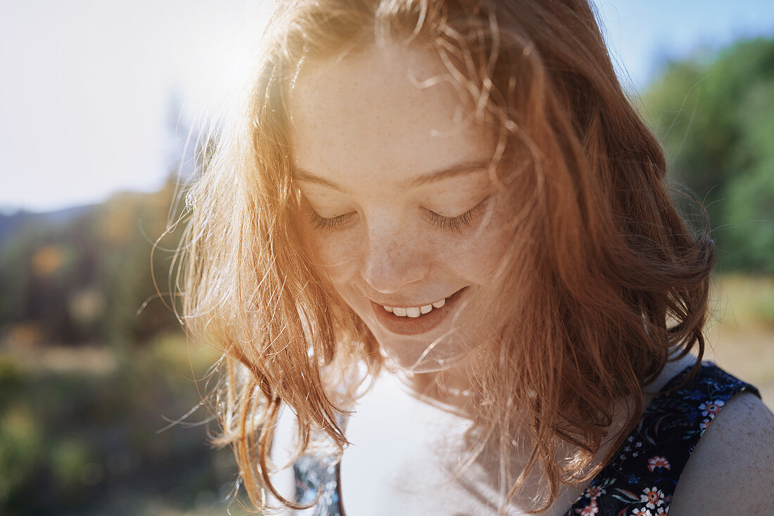 Smiling young woman with freckles looking down