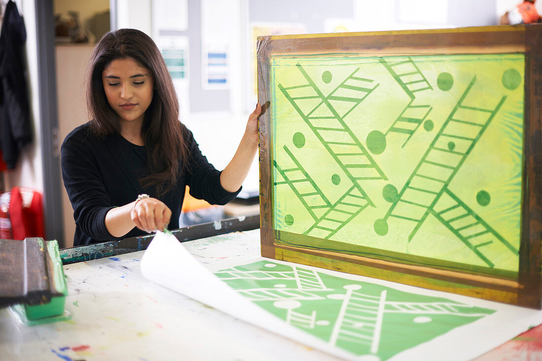 Female artist screen printing in studio