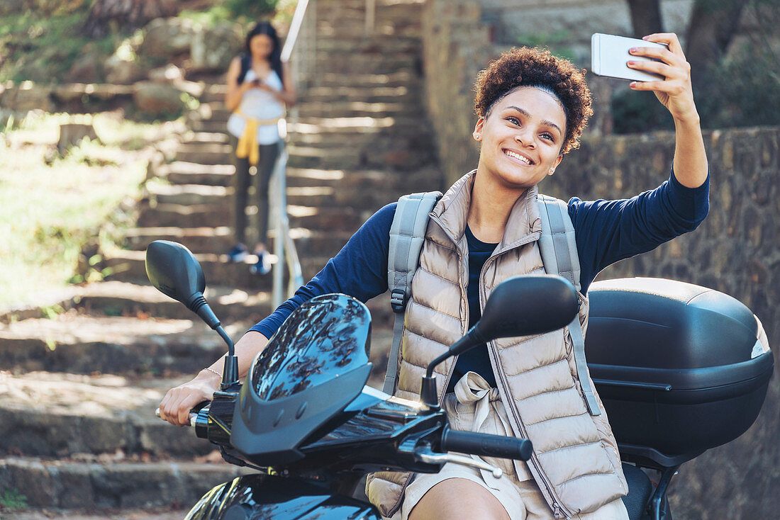 Young woman taking selfie on motor scooter