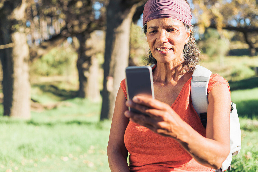 Female hiker using smart phone in sunny woods