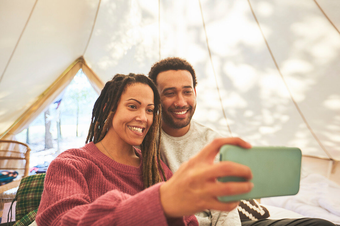 Happy couple taking selfie in camping yurt